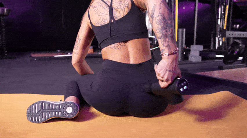 Korištenje masažnog pištolja na donjem dijelu leđa Korištenje masažnog pištolja na donjem dijelu leđa